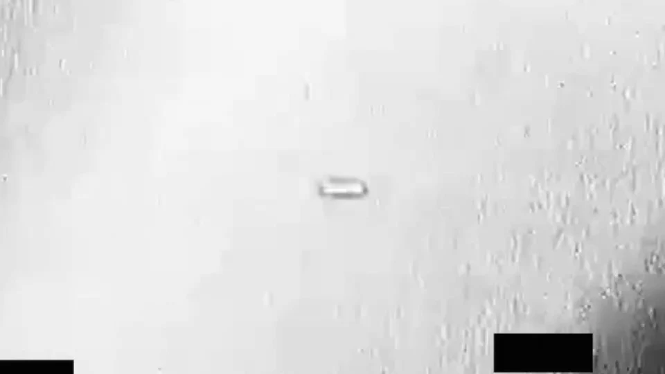 Almost white, saturated background with a horizontally elongated, capsule-like shape in the center and a black block at bottom right.
